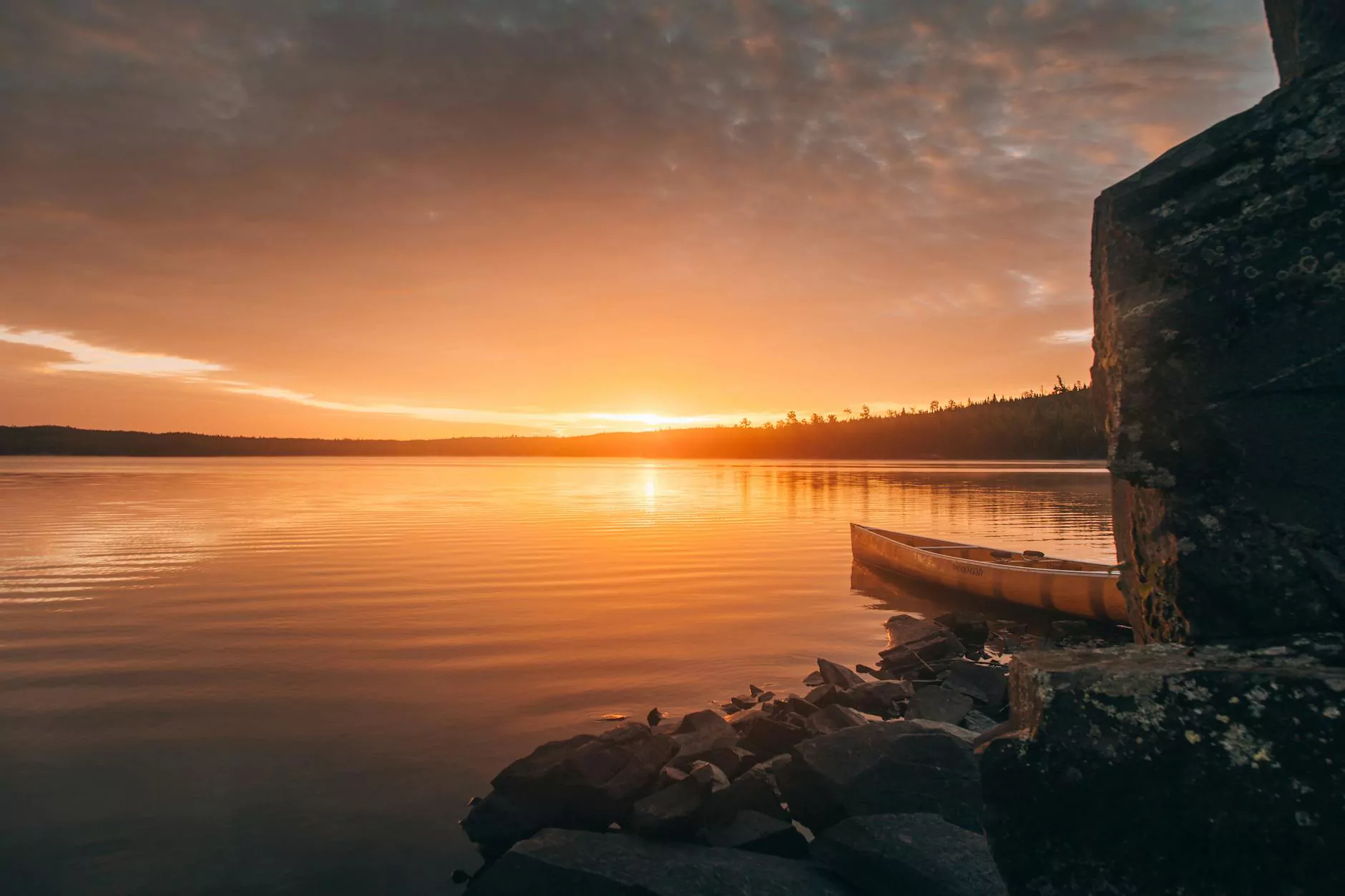 Evening light reflected on a quiet lake beside a rocky shore